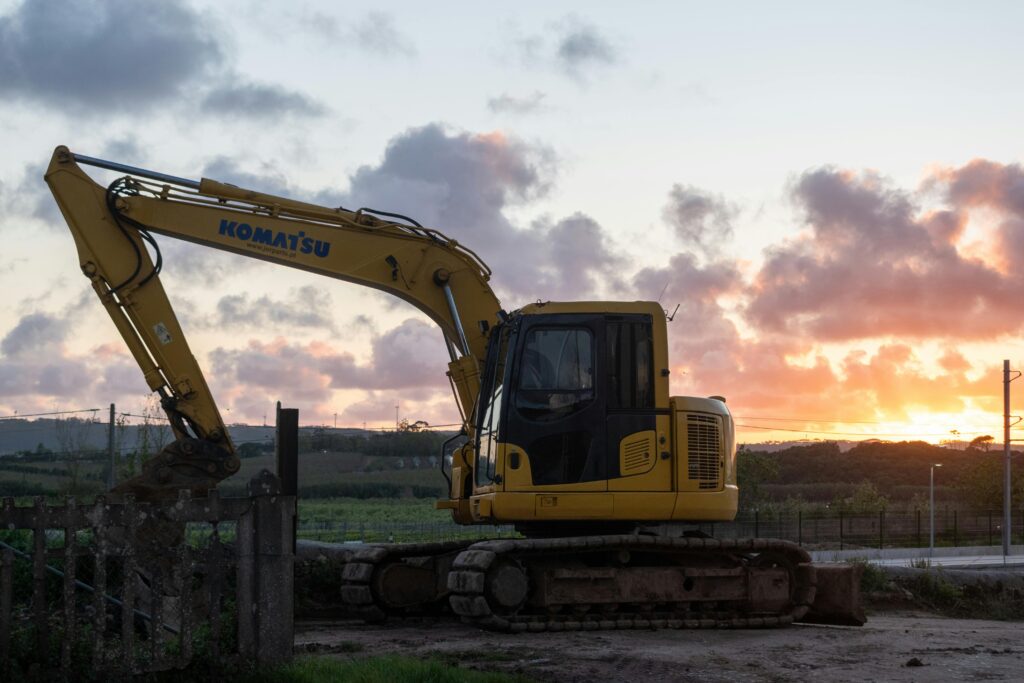 Silhouette of excavator working at sunset on a construction site with vibrant sky.