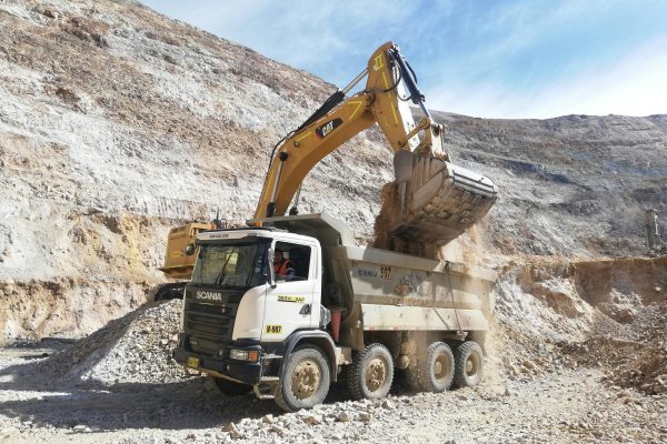 Excavator loading dump truck in a quarry. Industrial mining equipment scene.